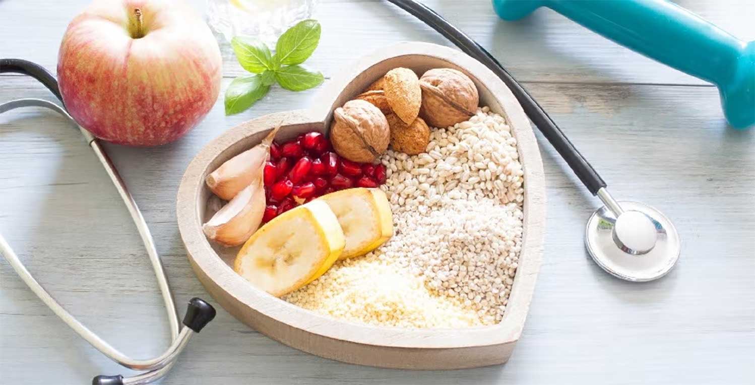 A heart-shaped bowl of grains, nuts and fruits. A stethoscope is draped behind it.