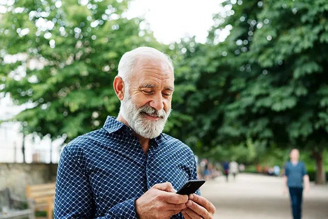 A man standing outside is using his phone to pay his medical bills