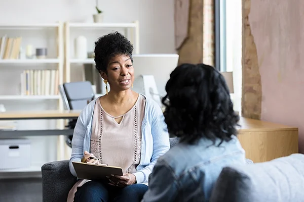 A woman counsels a female patient inside a modern-looking office